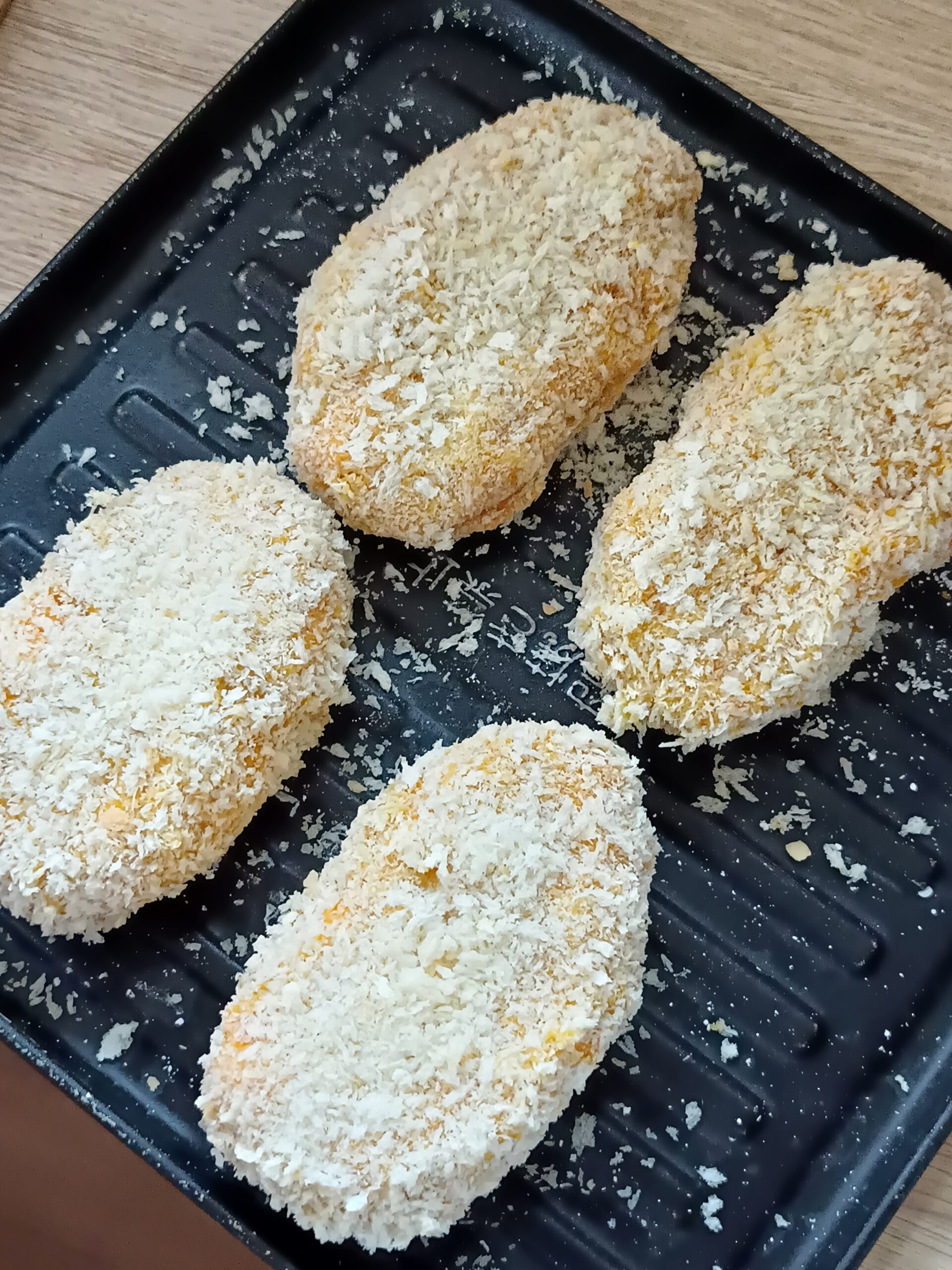 パン粉をまぶし、手で優しくギュッと押さえるようにして、隙間なく全体に密着させる様子