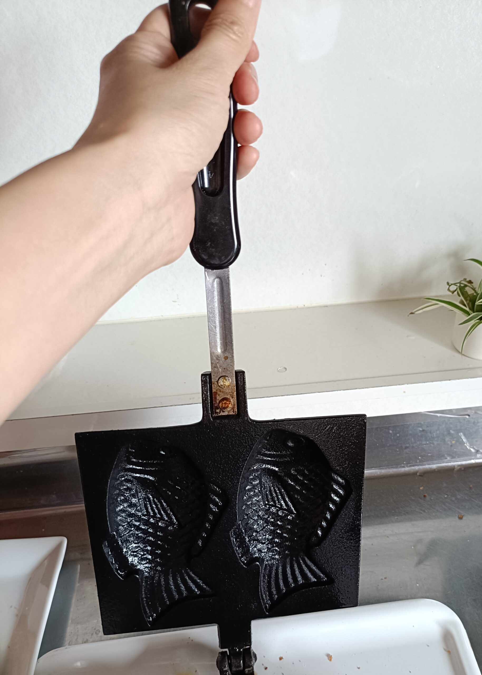 南部鉄器を開いて上の持ち手を持ちながら汚れを払い落とすところ